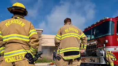 Two firefighters next to a firetruck during a training exercise
