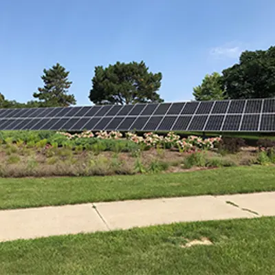 Large solar panel outside the Municipal Building behind a patch of flowers. 
