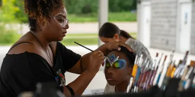 Woman painting the face of a young girl