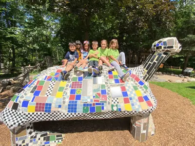 Six children sitting on the turtle sculpture at the Harris Nature Center