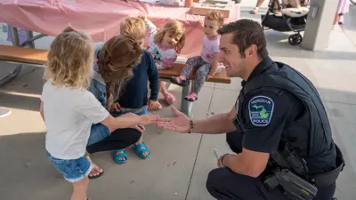 Meridian Township Police officer talking with a parent and children at an event